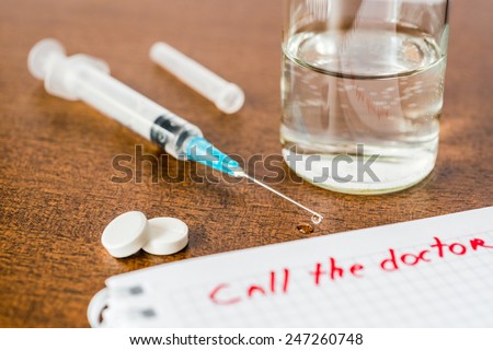Call the doctor, medicine flows from the syringe and spread out on the table. Angle view