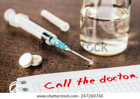Call the doctor, medicine flows from the syringe and spread out on the table. Angle view, focus on the sign, in old tones
