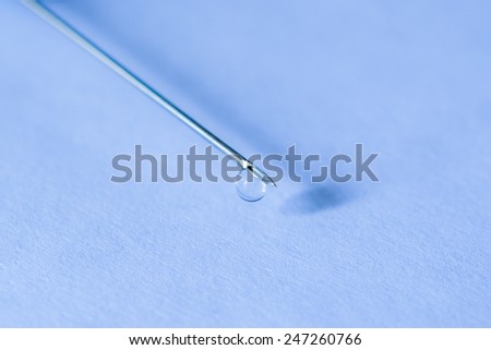 Medicine flows from the syringe and spread out. Angle close up view, in blue tones