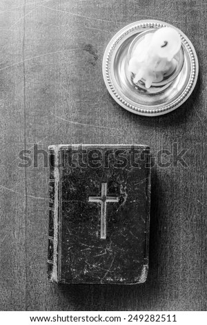 Candle and Bible on the wooden desk. In black and white tones