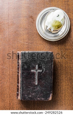 Candle and Bible on the wooden desk. In old tones
