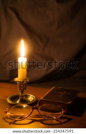 Old bible and candle on a wooden table