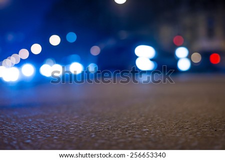 Nights lights of the big city, close up view from asphalt level on the lights of cars. In blue tones
