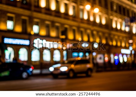 Nights lights of the big city, glowing shop windows and cars on the avenue