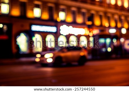 Nights lights of the big city, glowing shop windows and cars on the avenue. Image in yellow-blue toning