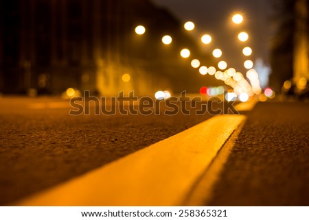 Nights lights of the big city, the night avenue with road markings, close up view from asphalt level