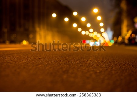 Nights lights of the big city, the night avenue with lanterns, close up view from asphalt level