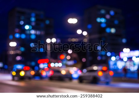 View of the city at night after the rain, shop windows and the car driving on the road. In blue tones