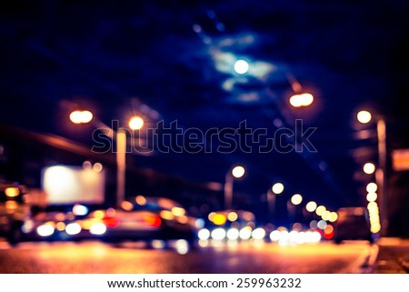 Night city after rain, the moon over the road on which the car ride. View from ground level, image in the yellow-blue toning