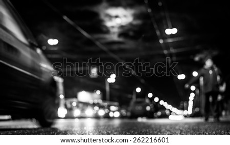 Nightlife, man catches a taxi voting on the sidelines at moonlit night. In black and white tones