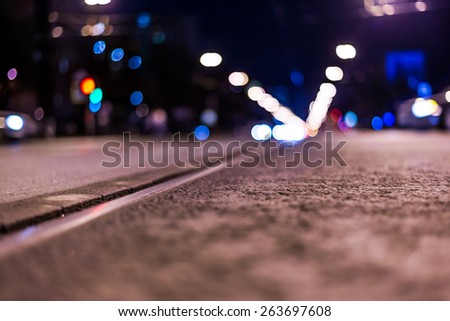 Night highway with rails, cars go over it. View from the level of asphalt, in blue tones