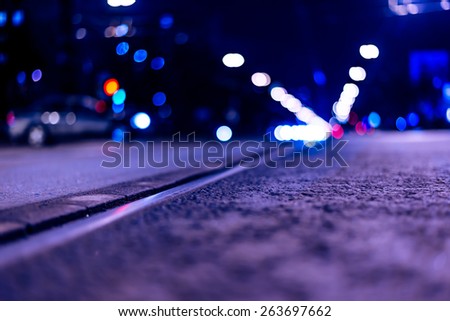 Night highway with rails, cars go over it. View from the level of asphalt, image in the blue toning