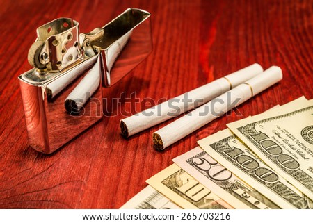 Couple of cigarettes with white filters and a several dollar bills with lighter on the table. Focus on the cigarettes