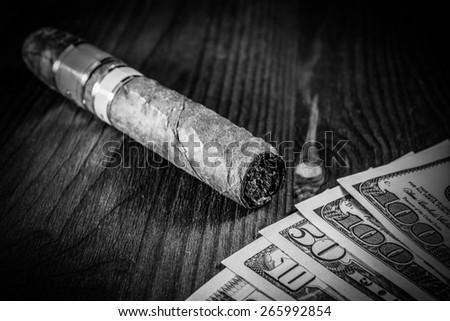 Cuban cigar and a several dollar bills on the table. Image vignetting and black and white tones