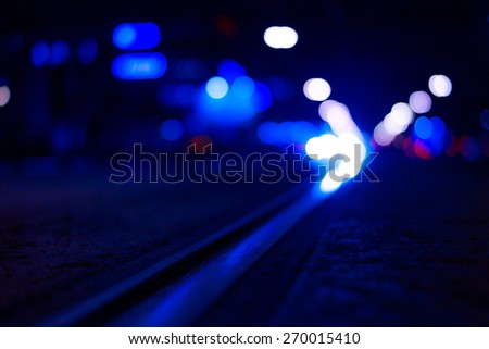 Night highway with rails, cars go over it. View from the level of asphalt, image in the blue toning