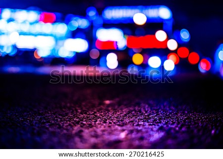 Nights lights of the big city, glowing shop windows and cars on the avenue. Image in the purple-blue tones