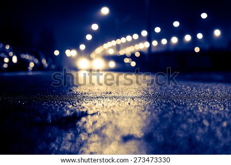 City night lights, road bridge with the lights and moving car in the fog after rain. View from the level of asphalt, image in the yellow-blue toning