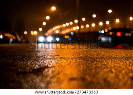City night lights, road bridge with the lights and moving cars in the fog after rain. View from the level of asphalt