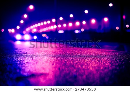 City night lights, road bridge with the lights and moving car in the fog after rain. View from the level of asphalt, image in the purple-blue toning