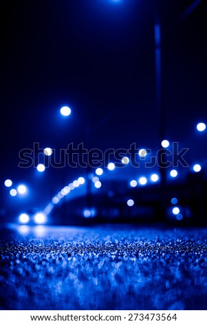 City night lights, road bridge with the lights and moving car in the fog after rain. View from the level of asphalt, image in the blue toning