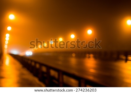 The bright lights of the city at night, the headlights of the approaching car on the road bridge. Defocused image