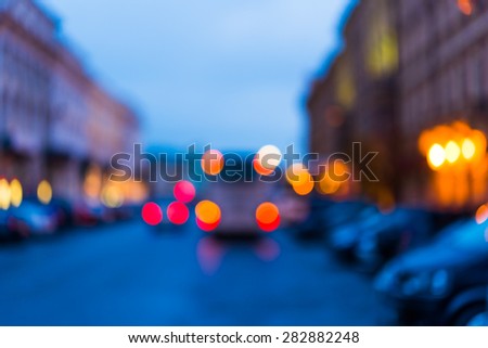 The bright lights of the evening city, the street going cars. Defocused image in blue tones