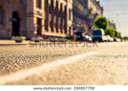 City on a sunny day, a quiet street with trees and cars. View from the dividing line, image in the yellow-blue toning