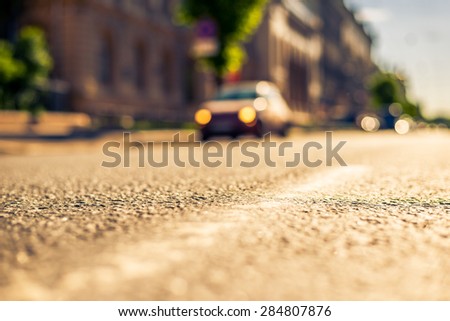 City on a sunny day, a quiet city street on which the car travels. View from the level of asphalt, image in the yellow-blue toning