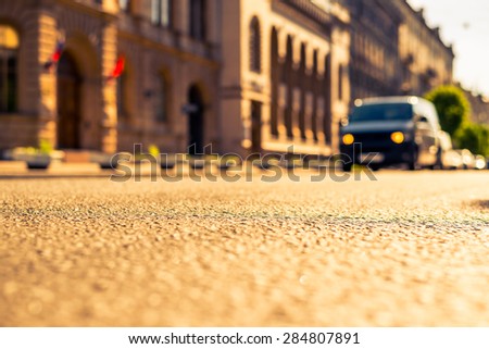 City on a sunny day, a quiet city street on which the van travels. View from the dividing line, image in the yellow-blue toning