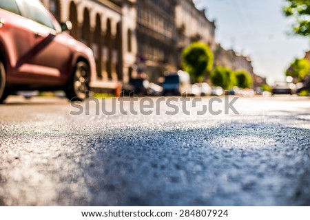 City on a sunny day, a quiet city street after rain on which passing car. View from the level of asphalt