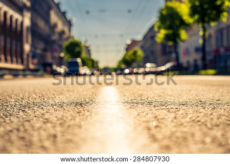 City on a sunny day, a quiet street with trees and cars. View from the dividing line, image in the yellow-blue toning