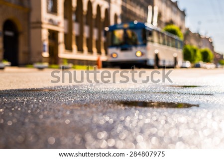 City on a sunny day, a quiet city street after rain on which the trolley travels. View from the level of asphalt
