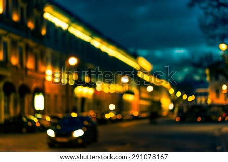 The bright lights of the evening city, the street going car. Defocused image, image in the orange-blue toning