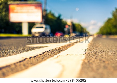 Sunny day in a city, view of the road with cars at the level of the dividing line. Image in the yellow-blue toning