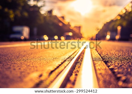 Sunny day in a city, view of the approaching cars from the level of the tram rails. Image in the orange-purple toning