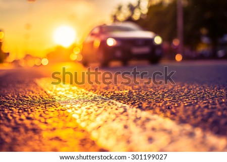 Sunny day in a city, view of the approaching car at the level of the dividing line. Image in the orange-purple toning