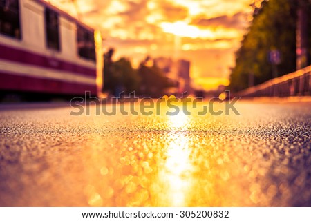 Sun after the rain in the city, the tram on the way, the view from the road level. Image in the yellow-purple toning