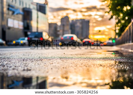 Sun after the rain in the city, view of the cars with a level of puddles on the pavement