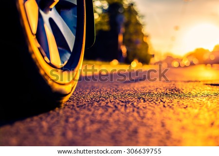 Sunny day in a city, headlights of approaching cars, the view from the road level from the wheel of the car. Image in the orange-purple toning