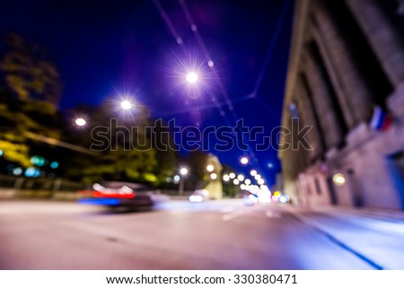 Nights lights of the big city, night avenue in the light of lanterns and driving car. Wide-angle view, defocused image, in blue tones