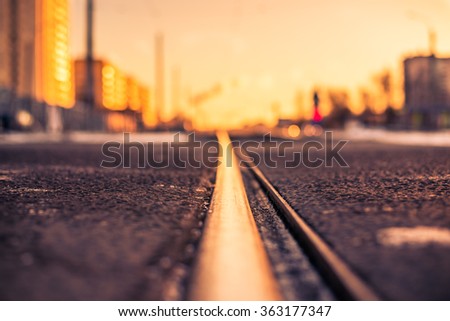 Bright winter sun in a big city, railroad tracks. View from the level of the snow-covered land, image in the orange-purple toning