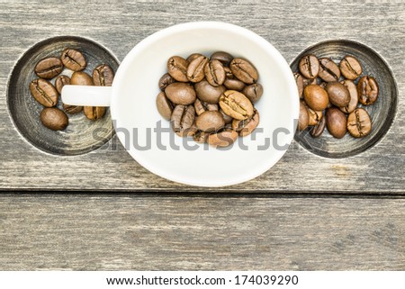 Fresh coffee beans in striped wood texture with circles carved in and white coffee cup