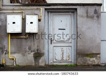 Old, wooden door and concrete wall with gas installation