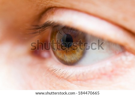 Macro photography of human brown eye with persons reflected in