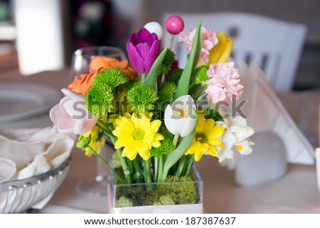 Floral arrangement on the table with white table cloth and other objects