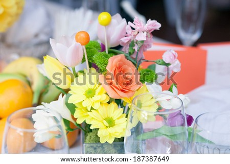Floral arrangement on the table with white table cloth and other objects