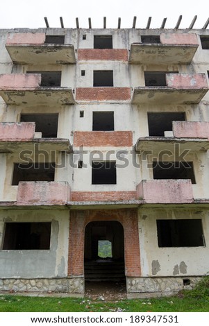 Abandoned block of flats under construction. Brick and cement textures with grass around it - details