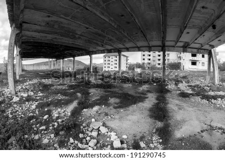 Black and white abandoned block of flats under construction and remains of an abandoned warehouse