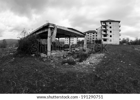 Black and white abandoned block of flats under construction and remains of an abandoned warehouse