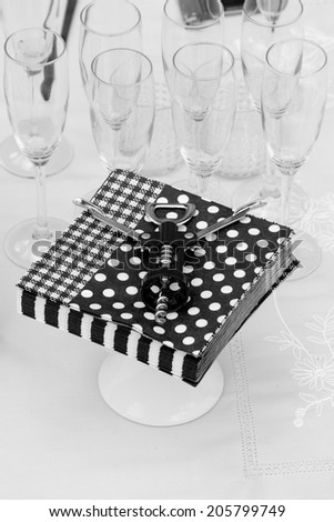 Black and white table arrangement with napkins, corkscrew and glasses